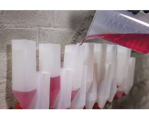 Nalévání červené tekutiny z odměrky do řady dávkovacích zásobníků