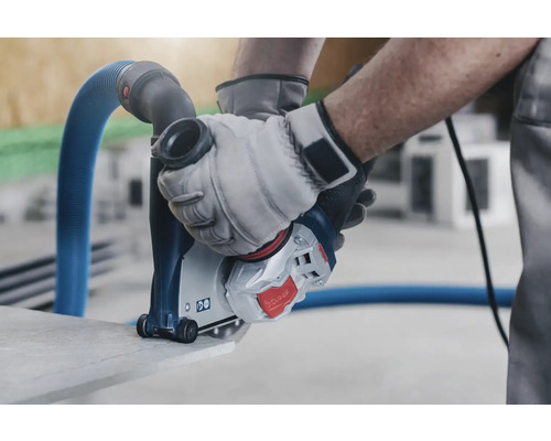 Muž používá drážkovací frézu se systémem odsávání prachu k řezání kamene