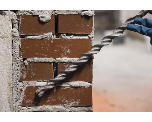 Spirála se zavádí do cihlové zdi.