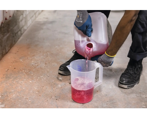 Osoba nalévá tekutinu z nádoby do odměrky.