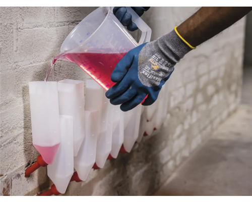 Osoba nalévá tekutinu z odměrky do řady trychtýřů připevněných ke zdi.