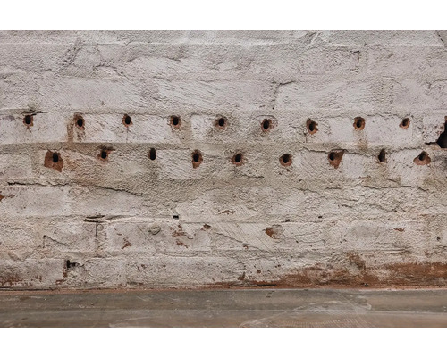 Detail cihlové zdi s vyvrtanými otvory.