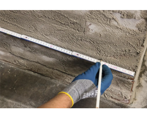 Osoba měří předmět skládacím metrem a tužkou.