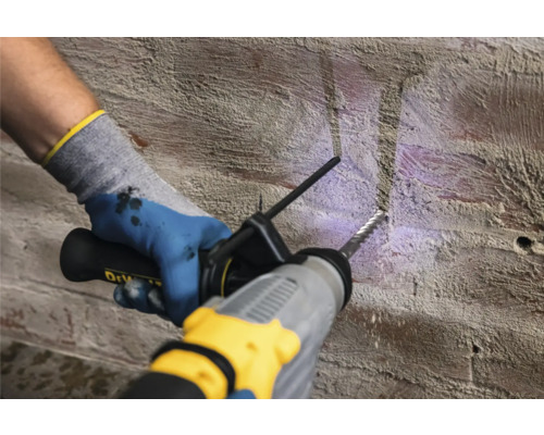 Osoba vrtá vrtačkou otvor do cihlové zdi.