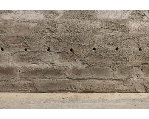 Zeď z cihel s vyvrtanými otvory.