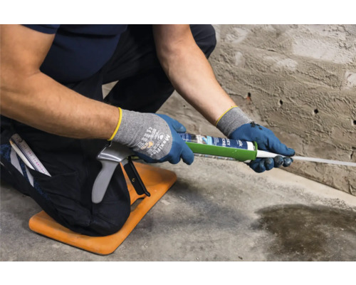 Řemeslník používá pistoli na kartuše k nanášení tmelu na zeď.