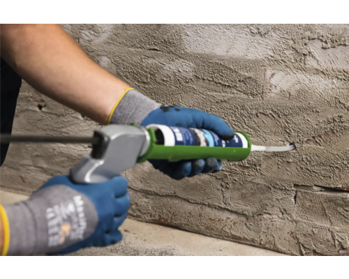 Řemeslník utěsňuje otvor ve zdi pomocí kartuše.