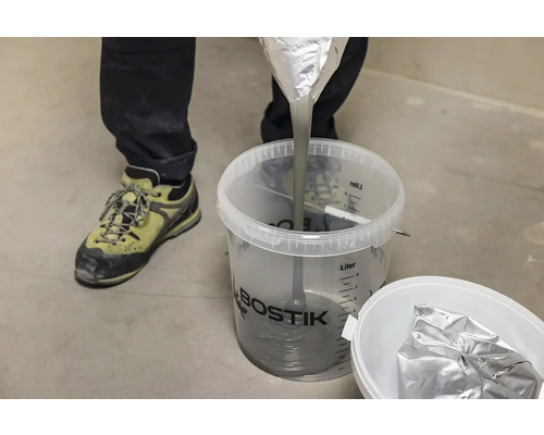 Osoba lije vyrovnávací hmotu do kbelíku od firmy Bostik