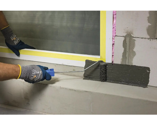 Nanášení těsnicí stěrky válečkem na beton.