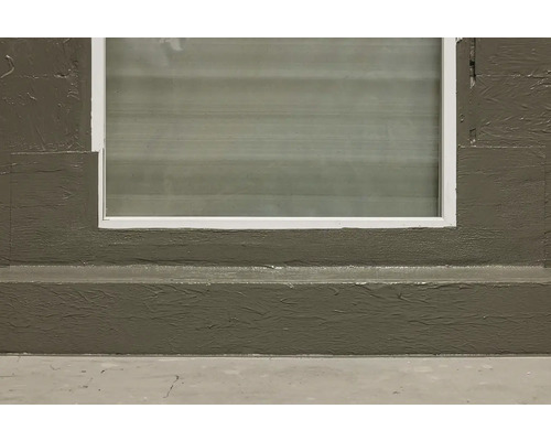 Sklepní okno s bílým rámem v betonové zdi