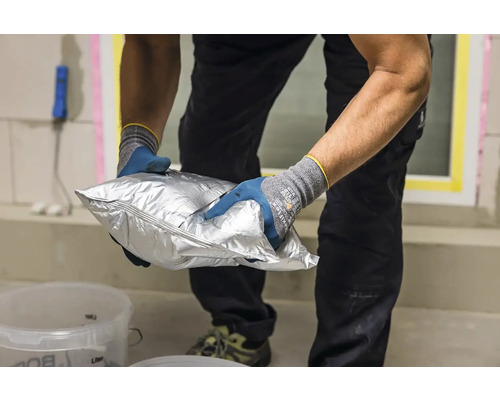 Muž drží stříbrné balení zdicí malty