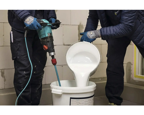 Dva řemeslníci míchají barvu míchadlem barev v kbelíku.