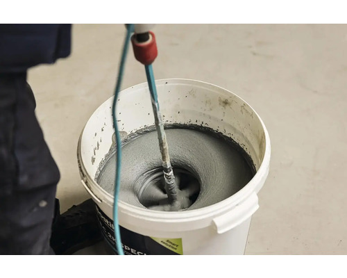 Míchání lepidla na obklady míchadlem ve vědru.