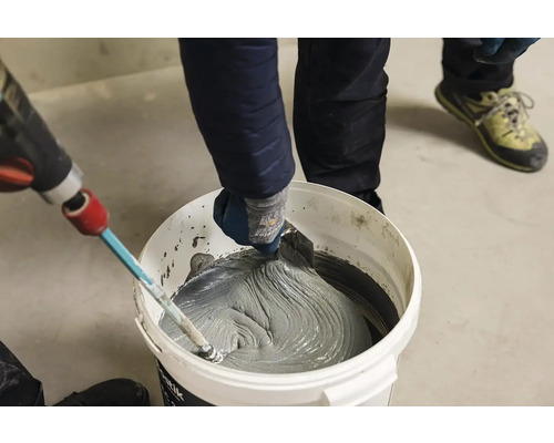 Míchání lepidla na dlaždice v kbelíku s míchacím zařízením