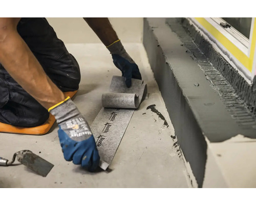 Řemeslník pokládá těsnicí pásku v interiéru.