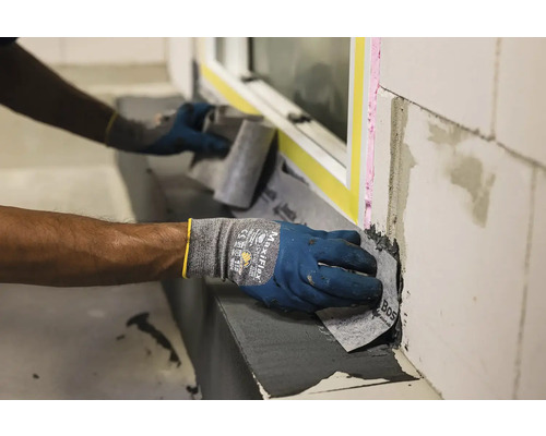 Osoba v rukavicích aplikuje těsnicí pásku na okno.