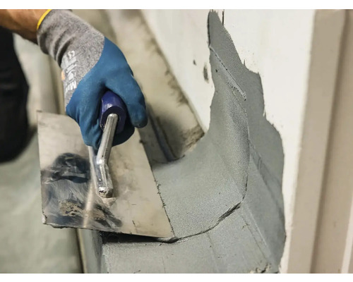 Zedník nanáší maltu na roh nerezovou lžící.