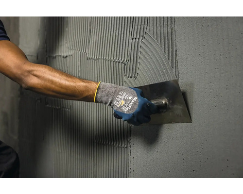 Nanášení lepidla na obklady hladítkem na stěnu