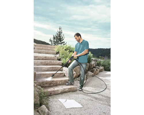 Muž čistí kamenné schody vysokotlakým čističem