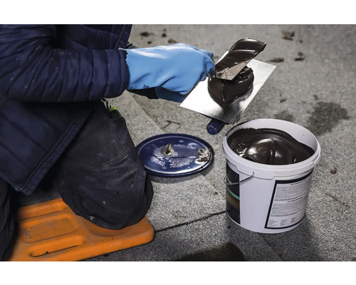 Pokrývač nanáší střešní těsnicí hmotu pomocí hladítka