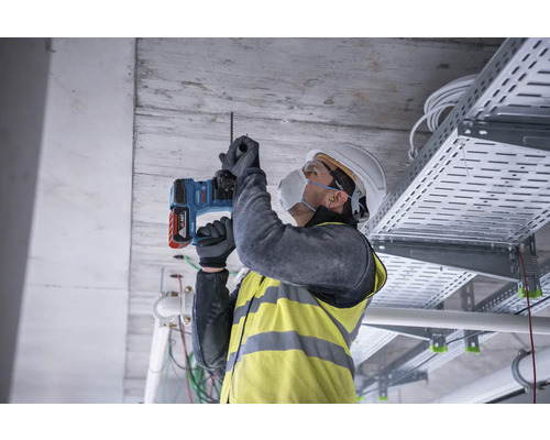 Řemeslník vrtá do stropu vrtacím kladivem.