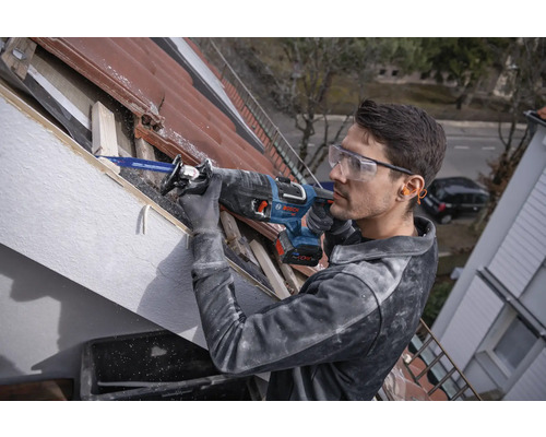 Muž pracuje s ocaskou na střeše