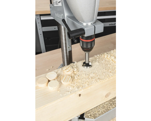 Stojanová vrtačka vrtá otvor do dřevěné desky s dřevěnými hmoždinkami