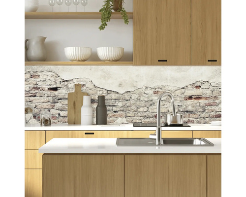 Kuchyňská scéna s dřevěnými skříňkami, dřezem, baterií a stěnou se vzorem cihel.