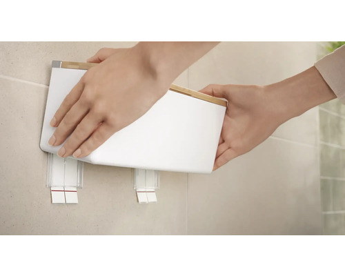 Osoba připevňuje dávkovač mýdla na nástěnný držák.