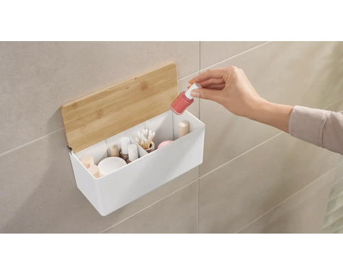 Nástěnný úložný box s kosmetikou a rukou, která do něj vkládá lak na nehty