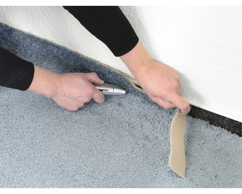 Řezání koberce u zdi pomocí řezacího nože