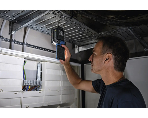 Muž kontroluje elektroinstalaci pomocí inspekční lampy.