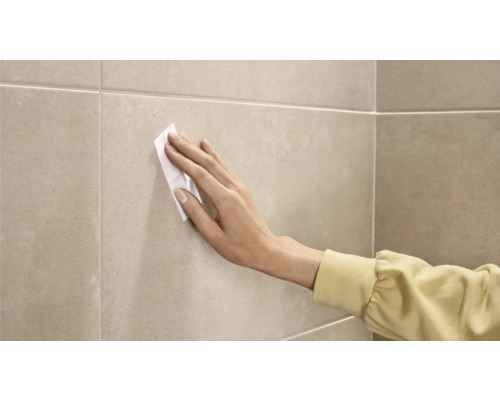 Osoba čistí dlaždice čisticím ubrouskem.