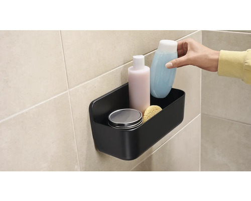 Černý sprchový košík s kosmetikou na zdi