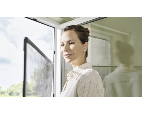 Žena se dívá na síť proti hmyzu na okně