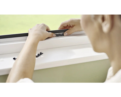 Osoba montuje síť proti hmyzu na okno