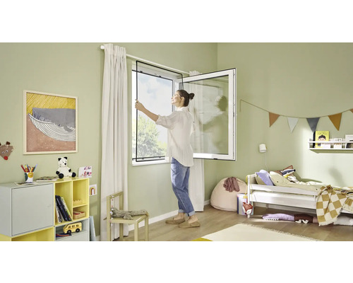 Žena montuje síť proti hmyzu na okno v dětském pokoji