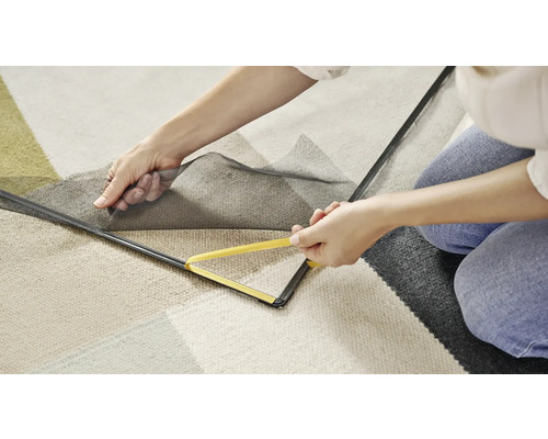 Žena připevňuje síť proti hmyzu s nářadím k okennímu rámu