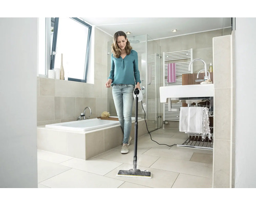 Žena čistí podlahu v koupelně parním čističem