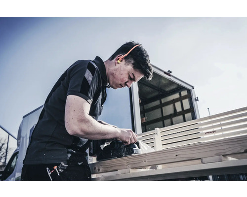 Řemeslník hobluje dřevo elektrickým hoblíkem venku