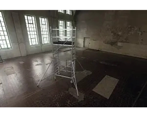 Lešení v prázdné místnosti s velkými okny pro stavební práce.