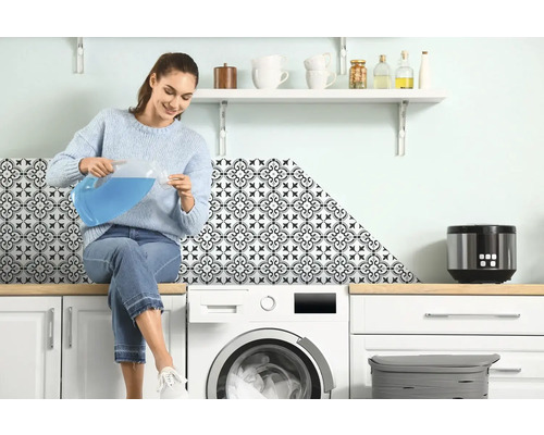 Žena sedí na pračce a nalévá tekutinu z džbánu do odměrky