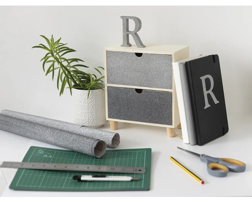 Dekorační scéna s komodou, rostlinou, zápisníky a řemeslnými materiály