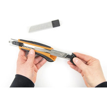 Ruce drží řezací nůž s náhradními čepelemi