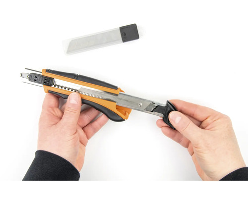 Ruce drží řezací nůž s náhradními čepelemi