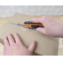 Osoba otevírá kartonovou krabici pomocí odlamovacího nože.