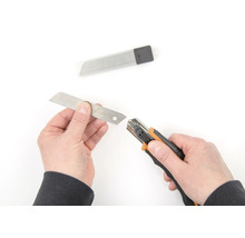 Ruce vyměňují čepel na řezacím noži