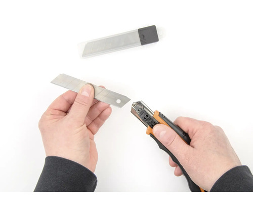 Ruce vyměňují čepel na řezacím noži