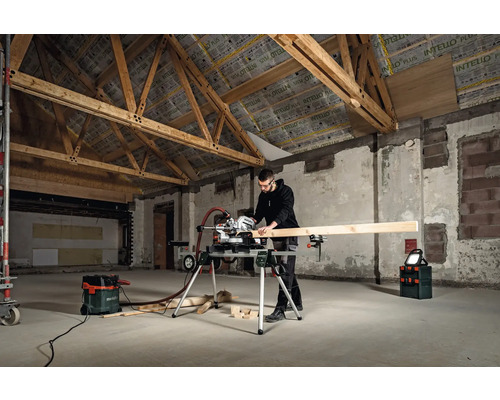 Muž řeže dřevo pokosovou pilou v nezrekonstruovaném pokoji.