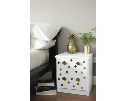 Dekorativní ložnice s bílým nočním stolkem, zdobeným kruhy a zlatými akcenty